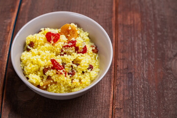 Steamed couscous with dogwood, nuts and raisins in a plate on the table
