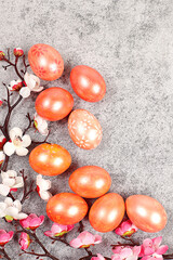 Easter celebration concept, marble Easter eggs painted with golden turmeric on concrete background with sakura branches, ideas for homemade Easter dishes