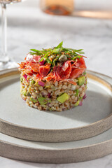 Superfood buckwheat tartare with avocado, capers and red onion, topped with serrano jamon slices