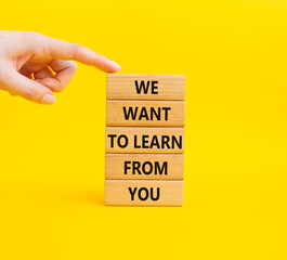 Naklejka premium We want to learn from you symbol. Wooden blocks with words We want to learn from you. Businessman hand. Beautiful yellow background. Business and We want to learn from you. Copy space.