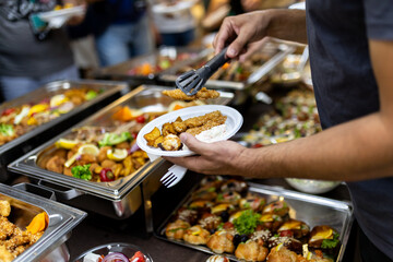 Gathering of friends enjoying a buffet meal with assorted dishes at a lively event in the evening setting