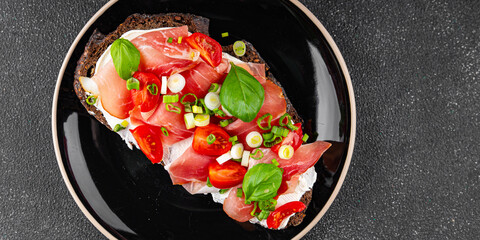 Bruschetta ham, tomato, greens dish fresh delicious gourmet food background on the table rustic food top view copy space