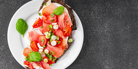 Bruschetta ham, tomato, greens dish fresh delicious gourmet food background on the table rustic food top view copy space