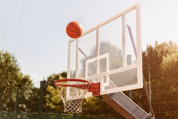 Basketball ball going through basket at outdoor sports arena, copy space