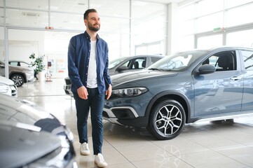 Young man is choosing a new vehicle in car dealership