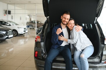 First big buy together. Portrait of a happy young couple hugging in a car salon