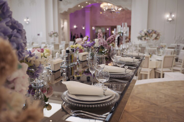 Elegant banquet table adorned with floral arrangements and soft lighting, creating a romantic ambiance for a festive celebration in a luxurious venue