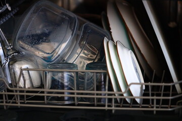 A close-up shot of a dishwasher filled with many dirty dishes and utensils.