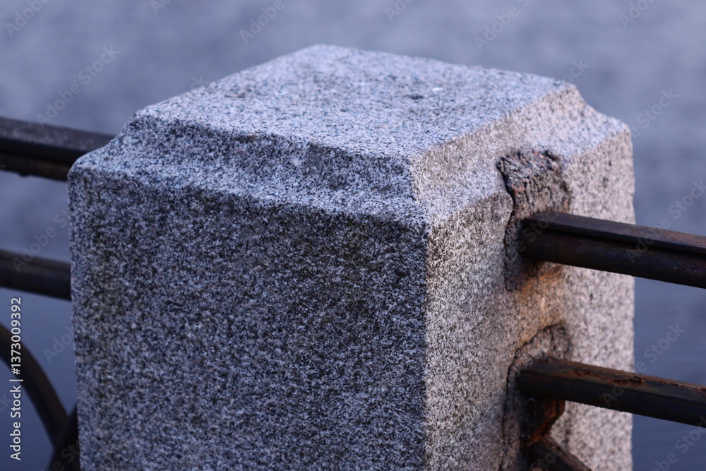 Poster A close-up shot of a metal fence with a stone block attached, suitable for use in architectural or decorative contexts.