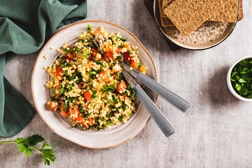 Tabbouleh salad with bulgur, tomato and parsley on a plate on the table top view