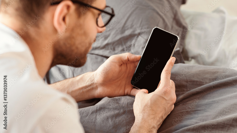 Poster Man Using Cellphone With Blank Screen Lying On Stomach In Bed At Home. Mobile Application Concept. Mockup, Panorama