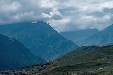 Obraz premium Breathtaking mountain ranges stretch across the horizon in Northern Ossetia, where dark clouds drift gracefully, enhancing the serene beauty of the landscape