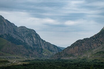 Breathtaking mountains rise dramatically in North Ossetia, their rugged formations adorned by lush greenery. A vast valley stretches below, inviting exploration and adventure