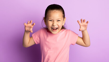 Funny Tiger. Portrait of cute playful little asian kid showing claws, purple studio background