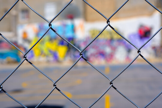 Urban playground behind chain-link fence with colorful graffiti in background