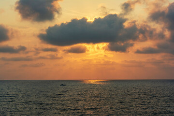 Obraz premium Sunset over calm sea with fishing boat