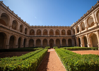 Fototapeta premium Renaissance-style courtyard featuring two-story limestone arcades surrounding formal gardens with geometric hedges under bright Mediterranean sunlight in Valencia, Spain