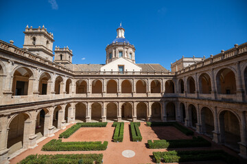 Fototapeta premium Historic Valencia Courtyard with Detailed Architecture and Manicured Garden Under Bright Blue Sky