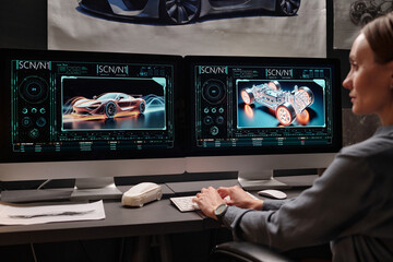 Focus on computer screens with 3d graphic models of new automobiles created by young female designer working in bureau
