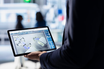 Technician in solar panel facility reviewing photovoltaic system performance on tablet. Close up of...