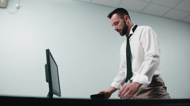 A businessman in aggression loses his temper in a fit of rage. An enraged office worker smashes a computer monitor with his keyboard, throws things off his desk and screams. Financial crisis or layoff