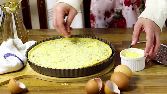 woman is preparing leek quiche and putting cheese