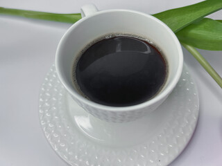 cup of coffee, on white background, laptop, orange-pink tulip bud, morning spring atmosphere