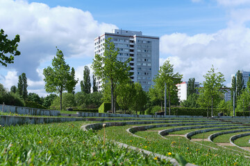 Curved tiered seating in a lush modern urban park at the edge of metropolitan City, with  tall...