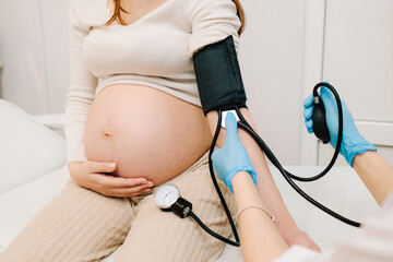 High pressure problem during pregnancy. Gynecologist measures blood pressure for pregnant patient...