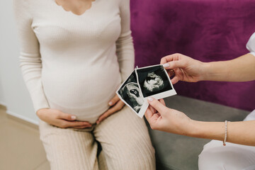 Gynecologist shows a sonographic picture of the baby to pregnant woman. Consulting pregnant patient about embryo health.