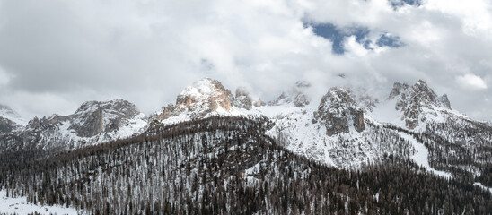 Snow covered peaks of the Dolomite Mountains near Cortina, Italy, framed by dense evergreen forests...