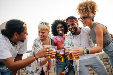 Happy friends toasting with beer at music festival