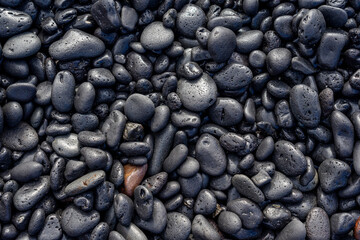 Round black volcanic stones on lanzarote ocean beach.
