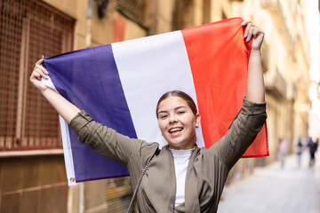 Cheerful female tourist displaying french flag in old town of city