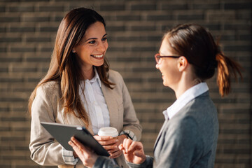 Businesswomen discussing over digital tablet while having coffee break