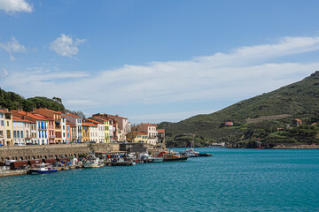 Fototapeta premium Charming buildings line the harbor as fishing boats bob gently in the calm waters. Port-Vendres, Occitanie, France
