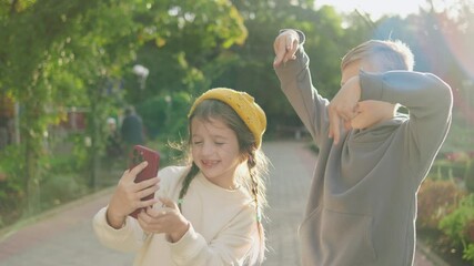 Children enjoy taking selfies in a park during a sunny afternoon while playfully posing with peace signs