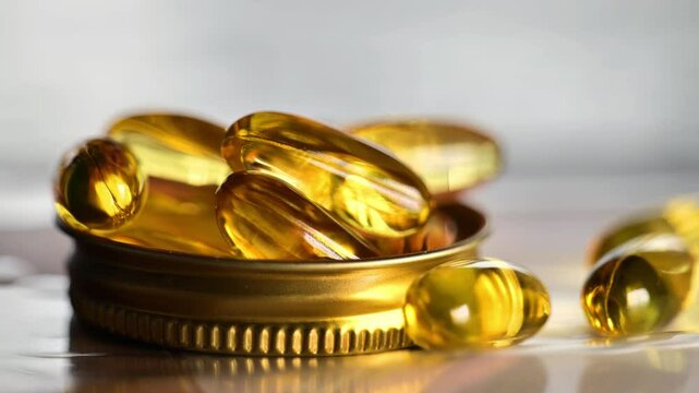 Yellow omega three capsules in hands on light background.Healthy fats and oils in nutrition. Omega acid gelatin capsules. 4k footage