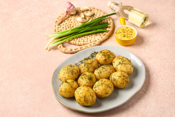 Plate of boiled baby potatoes with dill and green onion on pink background