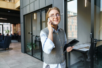 Young professional on a phone call while holding a tablet in a modern office setting during the day