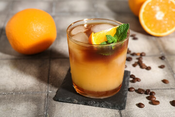 Glass of tasty orange espresso on grey tile background