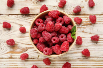 Bowl with fresh raspberry on light wooden background, closeup
