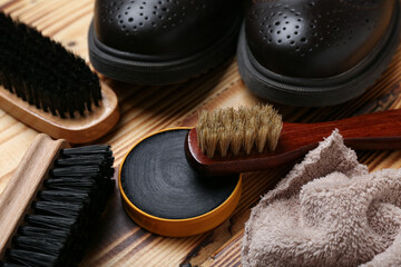 Brushes, shiny shoes, cloth and shoe polish on wooden background