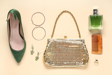 Golden bag, bottle of perfume and different woman's accessories on beige background