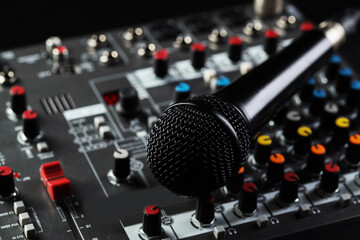 Professional mixing console with microphone on black background, closeup