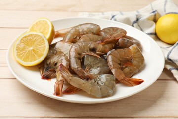 Fresh raw shrimps with lemon on wooden table, closeup