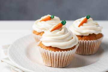 Tasty carrot muffins with cream on white wooden table, closeup