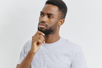 Pensive african american man in grey tshirt contemplating decision with hand on chin
