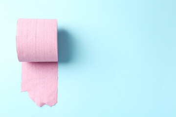 Pink toilet paper roll on light blue background, top view. Space for text