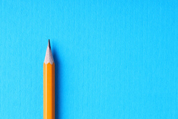 One pencil on light blue background, top view. Space for text